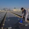 Un empleado mantiene limpias las instalaciones de una granja solar en China.