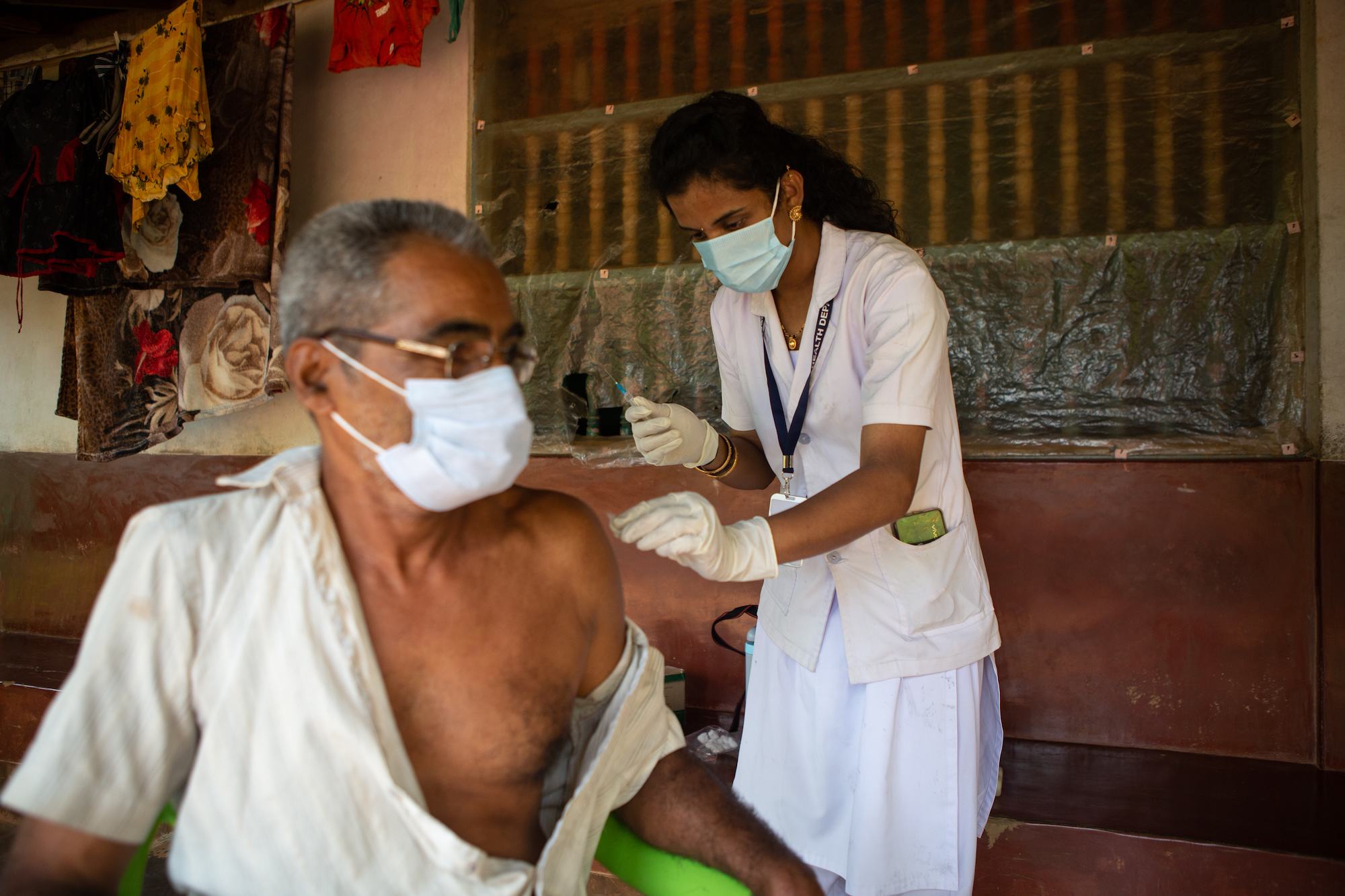 تقوم الممرضة بتطعيم رجل مسن ضد كوفيد-19.