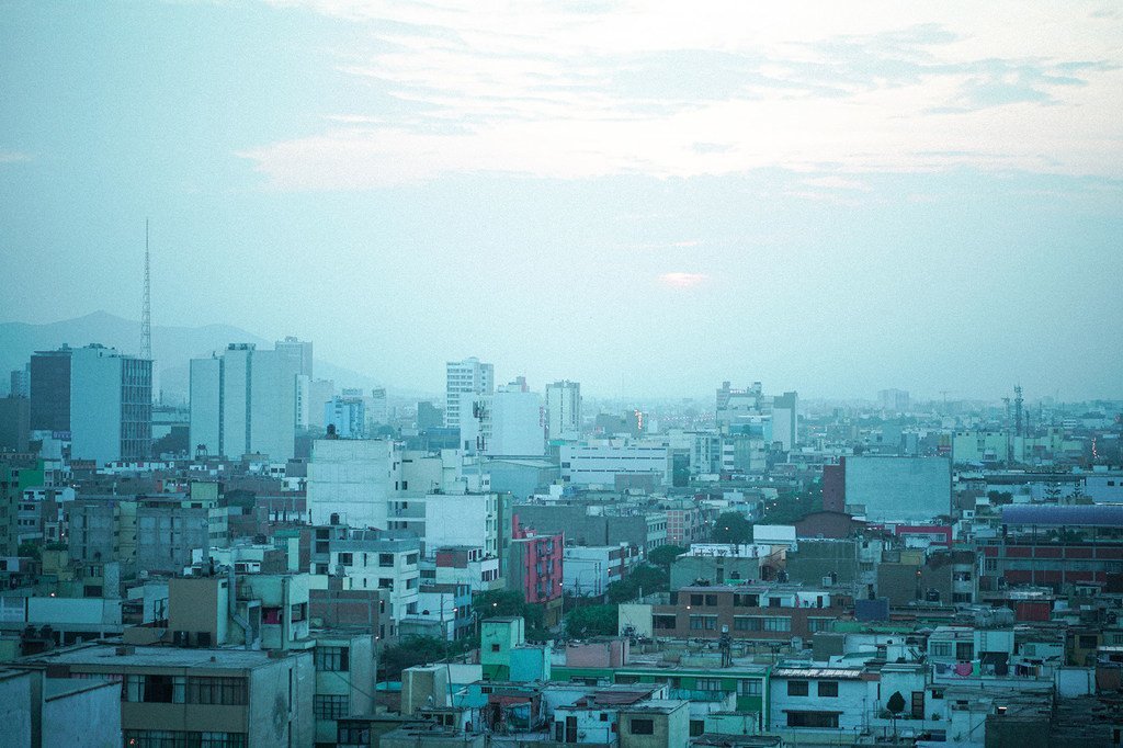 Una vista panorámica del horizonte de la ciudad de Lima, con edificios y montañas a lo lejos, en un día brumoso.