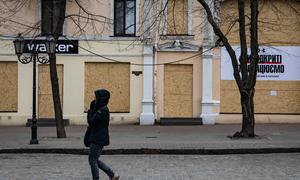 在乌克兰敖德萨，一名妇女走过被木板封住的商店。