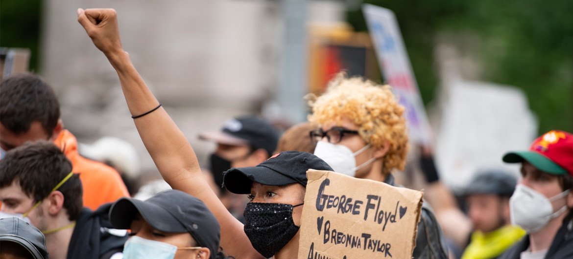 Em junho de 2020, manifestantes na cidade de Nova York exibem cartazes e levantam os punhos durante um protesto contra o racismo e a violência policial.