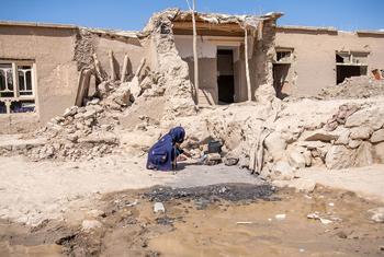 Humanitarian needs across Afghanistan are rising against a backdrop of shrinking fundamental freedoms. Pictured here, a woman boils water outside her home that was damaged by floods in northern Afghanistan.