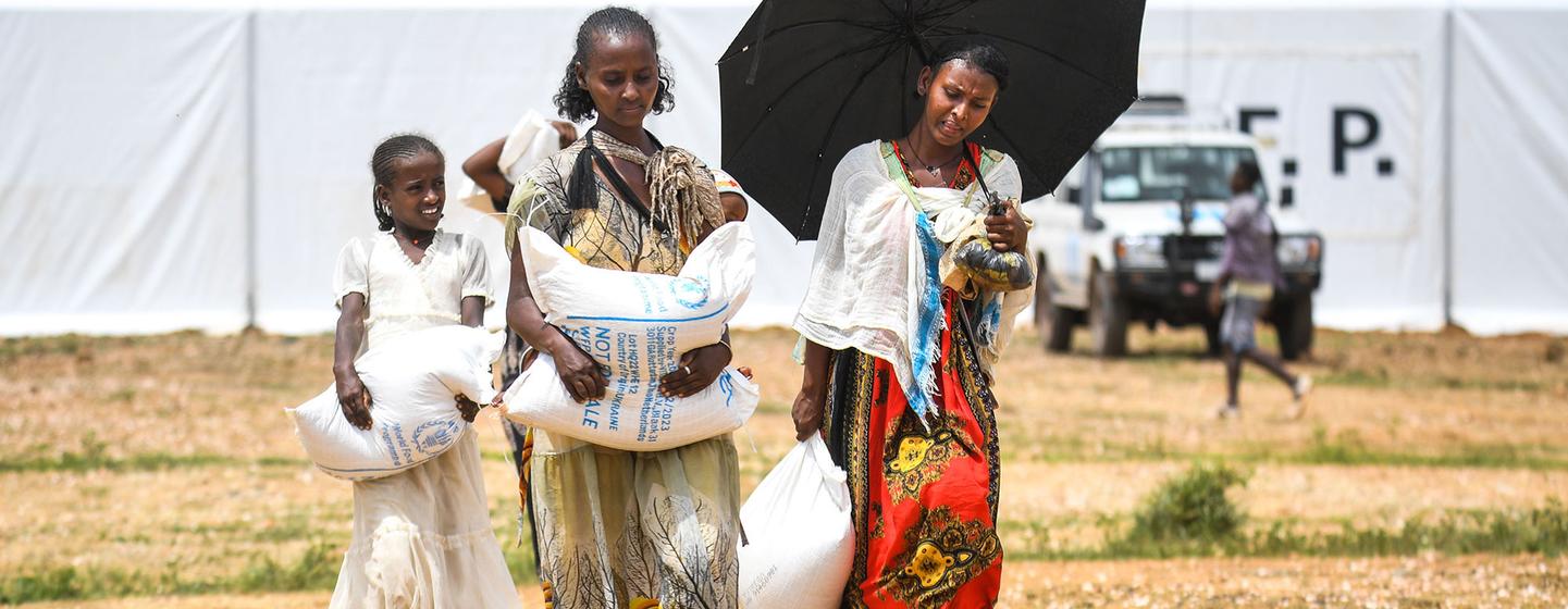 Abadit Siyum, 26 ans, mère de quatre enfants, porte l'aide alimentaire reçue du PAM dans la région du Tigray, en Éthiopie. L'image montre la reprise de la distribution de l'aide alimentaire après la mise en œuvre de l'enregistrement numérique pour les bénéficiaires.