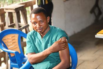 Un professionnel de santé vêtu de combinaisons vertes reçoit un vaccin contre l'Ebola dans une clinique en RDC.