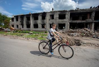 A boy rides his bike past destroyed homes in Chernihiv, Ukraine.