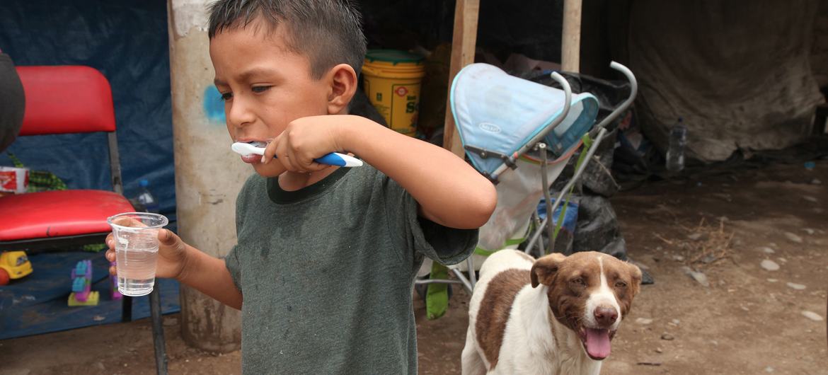 Un niño desplazado, cuya casa fue destruida por las inundaciones, se cepilla los dientes fuera de un refugio temporal en Lima, Perú.