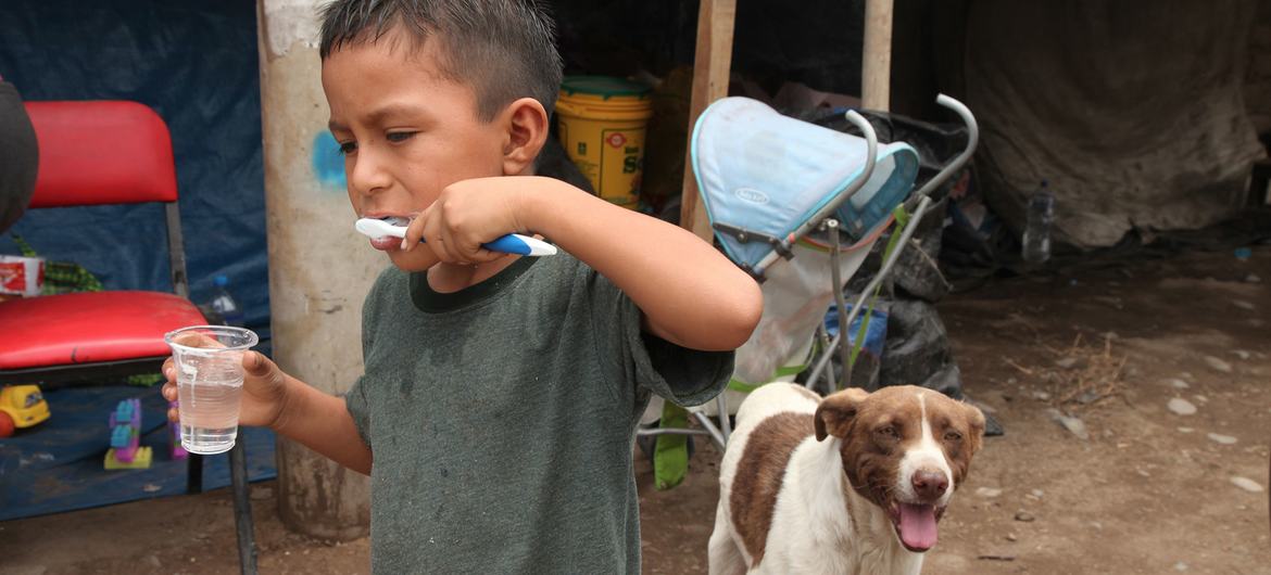 A displaced boy, whose home was destroyed by floods, brushes his teeth outside a temporary shelter in Lima, Peru. A displaced boy, whose home was destroyed by floods, brushes his teeth outside a temporary shelter in Lima, Peru.