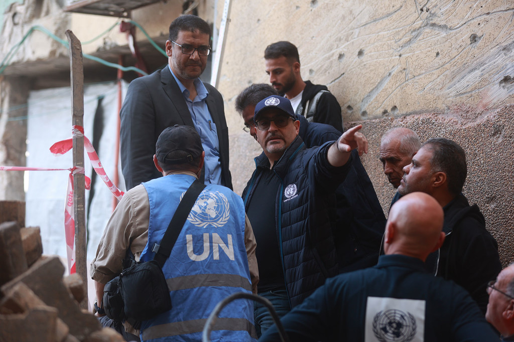 الأمين العام الأمم المتحدة أنطونيو غوتيريش وموظفو الأمم المتحدة يتفقدون مبنى مدمرًا في غزة.