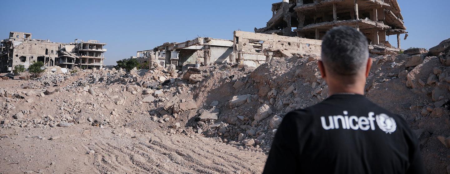 Qays Sheikh Najib, ambassadeur de l'UNICEF en Syrie, se tient avec le dos à la caméra en observant les décombres d'immeubles détruits à Jobar, Damas rurale, en Syrie, le 18 novembre 2025.