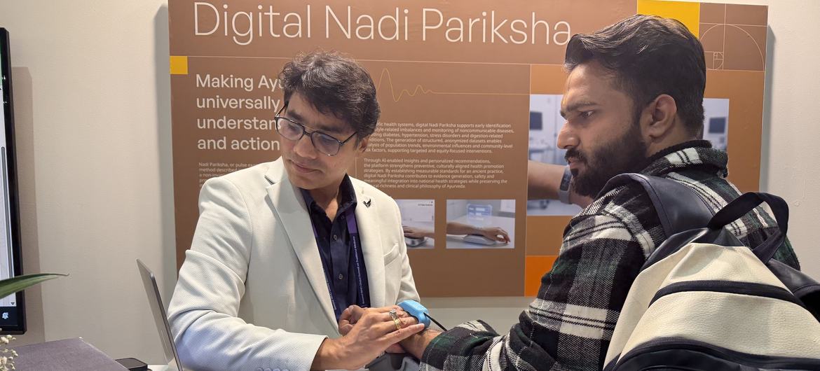 एक चिकित्सक भारत में डब्ल्यूएचओ के पारंपरिक चिकित्सा शिखर सम्मेलन में एक आगंतुक पर डिजिटल नाडी परिक्षा, एक आधुनिक आयुर्वेदिक पल्स रीडिंग तकनीक का प्रदर्शन करता है।