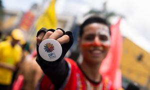 A young man displays a button with the official COP16 image at a carnival march in Ibagué, Tolima.