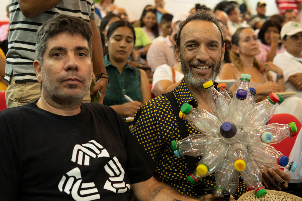 Participantes en uno de los actos previos a la COP16 en la Universidad del Valle, con comunidades y agentes sociales. A la izquierda, un hombre muestra la flor Inírida, logotipo oficial de la Conferencia, hecha con botellas recicladas.