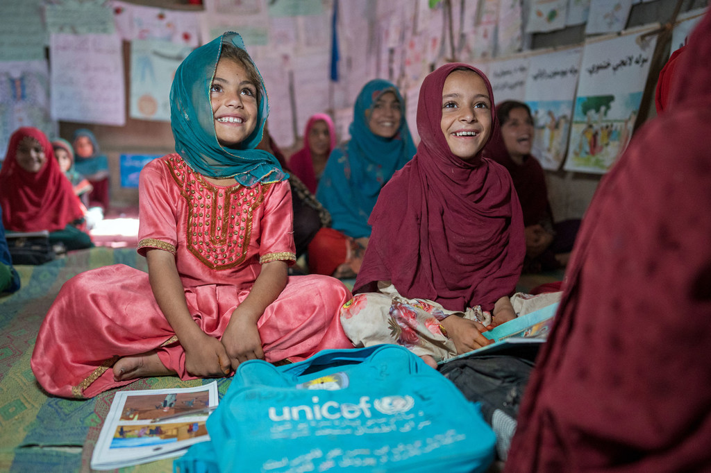 Niñas afganas sonrientes en un aula de una escuela apoyada por UNICEF.