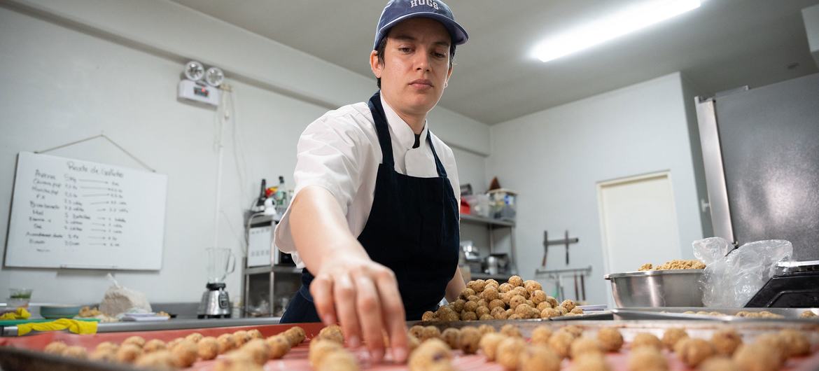 Em Lima, no Peru, um padeiro organiza produtos de panificação em uma bandeja em uma cozinha comercial.