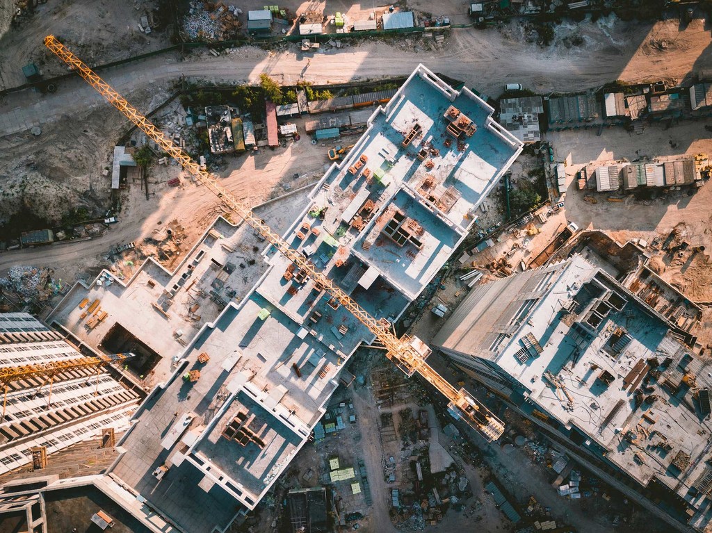 Vista aérea de una obra en construcción con edificios en edificación y una gran grúa amarilla.