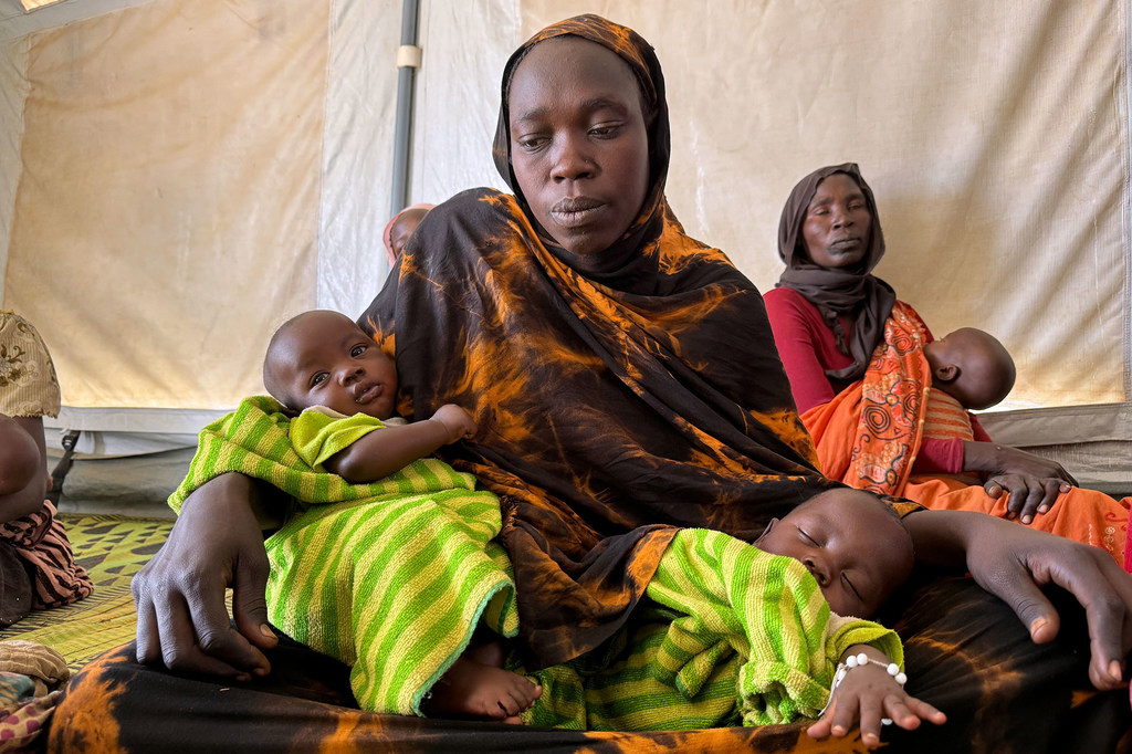 لاجئة سودانية تجلس مع توأمها البالغين من العمر ثلاثة أشهر في مركز للتوعية بالرضاعة الطبيعية والتغذية تدعمه اليونيسف في شرق تشاد.