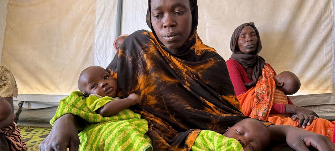 Uma refugiada sudanesa senta-se com seus gêmeos de três meses em um centro de conscientização sobre amamentação e nutrição apoiado pela Unicef no leste do Chade