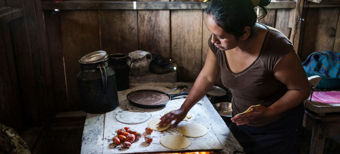 Uma mulher cozinha tortilhas de milho para alimentar sua família