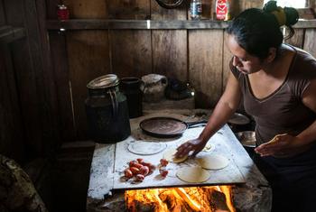 Uma mulher cozinha tortilhas de milho para alimentar sua família