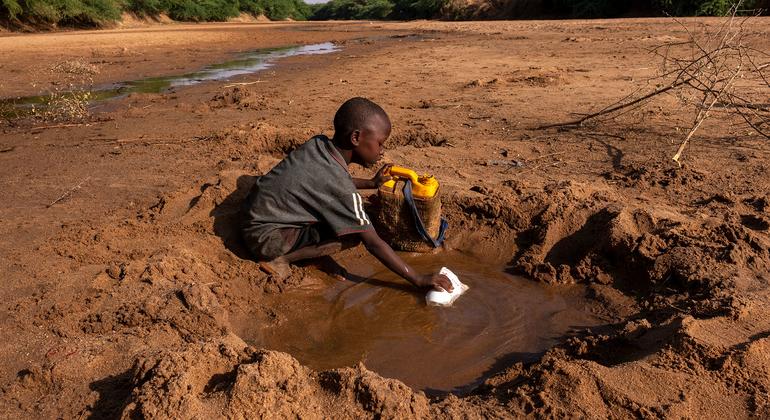 Een jonge jongen verzamelt zo weinig mogelijk water uit een rivier die is opgedroogd door ernstige droogte in Dolo, Somalië.