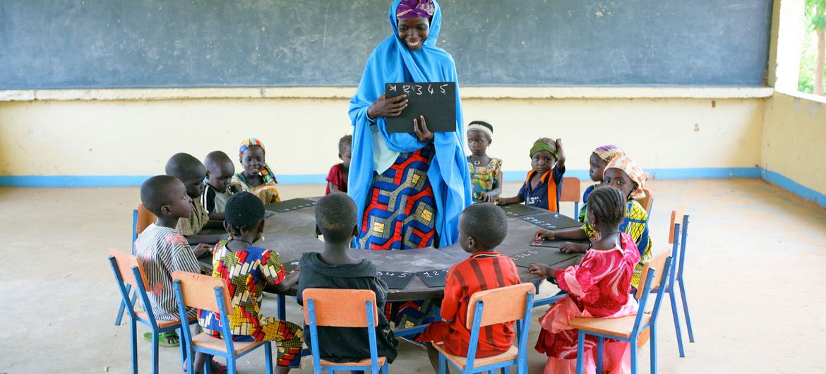 As crianças sentam-se em círculo com a professora no centro de desenvolvimento da primeira infância na aldeia de Garin Badjini, no sudeste da Nigéria