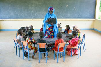 Des enfants en cercle autour de leur enseignante dans un village au sud-est du Nigéria.