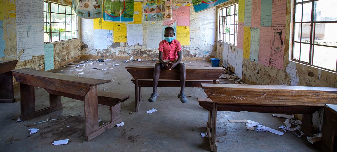 Um menino de 12 anos senta-se na sala de aula vazia de uma escola que foi fechada durante a pandemia de Covid-19