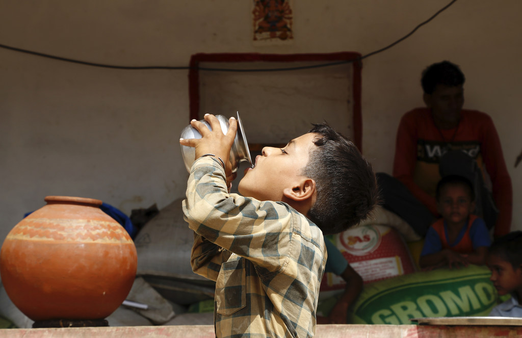 भारत के राजस्थान में एक ग्रामीण घर में भीषण गर्मी के दौरान एक नौ वर्षीय लड़का धातु के कप से पानी पी रहा है।