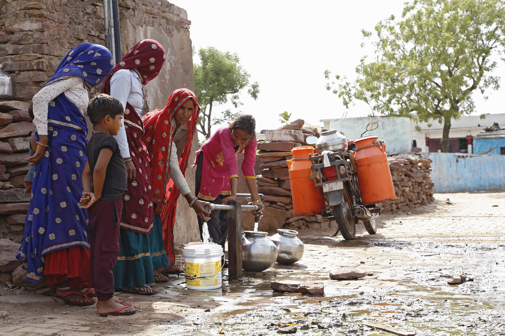भारत के राजस्थान राज्य के करौली जिले के बरकी गांव में एक पारंपरिक जलाशय में महिलाएं और एक छोटा लड़का सौर ऊर्जा से चलने वाले पंप से पानी के बर्तन भर रहे हैं।