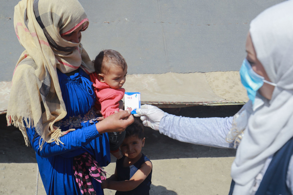 A mother in Raqqa city, Syria, goes to get medicine for her child with diarrhea and is also taught how to disinfect water to prevent cholera.