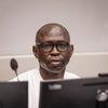 Maxime Jeoffroy Eli Mokom Gawaka ameketi kwenye dawati akiwa na kipaza sauti na kifaa cha kuchungulia kompyuta mbele yake.