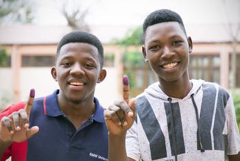 Two young men show the ink mark on their fingers after voting in the general elections in Mozambique.