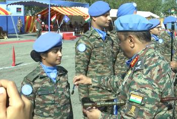 पदक परेड समारोह के दौरान UNMISS की वर्दी पहने भारतीय शांति सैनिकों को दिखाया गया है। एक अधिकारी एक महिला सैनिक को पदक प्रदान कर रहा है, जबकि नीली बेरेट और छलावरण वर्दी पहने अन्य सैनिक पास में खड़े हैं।