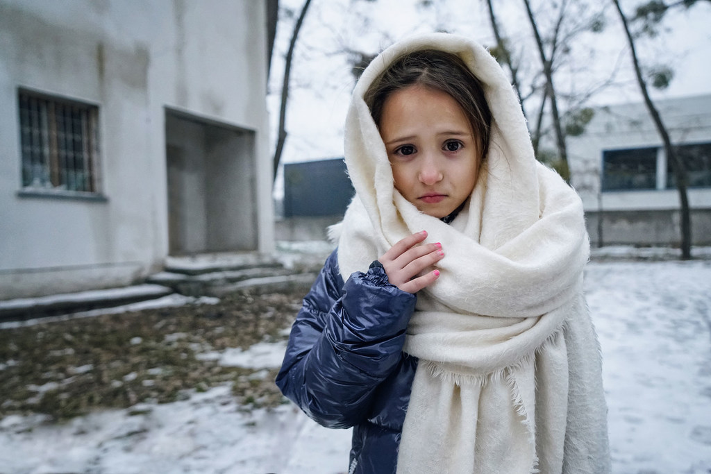 Une fillette de 8 ans pose devant un immeuble à Irpin, en Ukraine, où sa mère et sa sœur partagent une petite chambre.