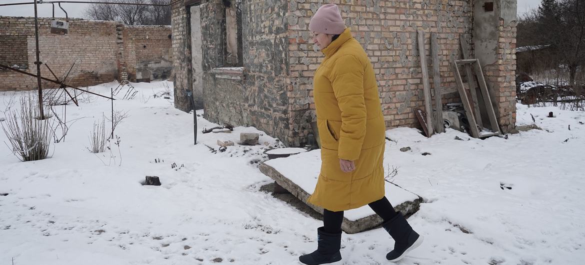 A woman walks past her damaged home in Horenka village in Kyiv Oblast.