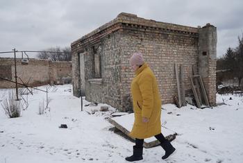 Une femme passe devant sa maison endommagée dans le village de Horenka, dans la région de Kiev.