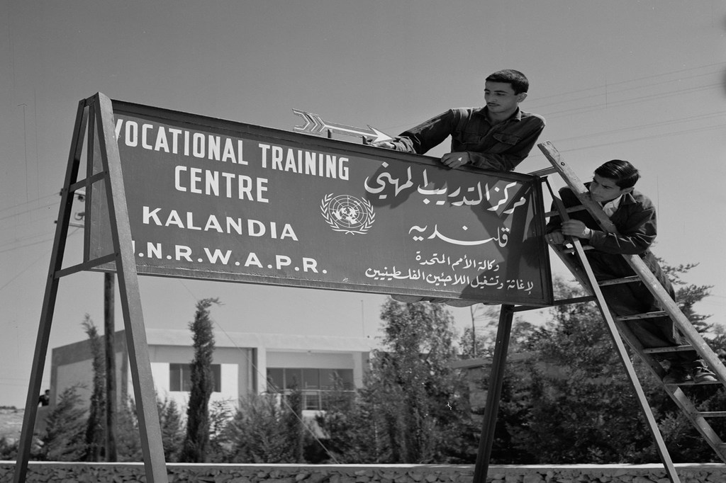 Deux hommes installent un panneau pour le centre de formation professionnelle UNRWA de Kalandia en Cisjordanie.