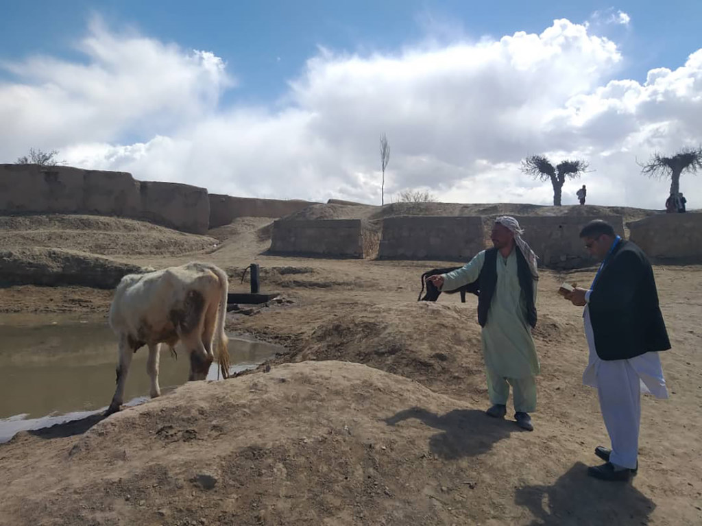 FAO का एक अधिकारी ग्रामीण गांव में एक पारंपरिक जल भंडार के पास एक अफगान किसान से बात कर रहा है।
