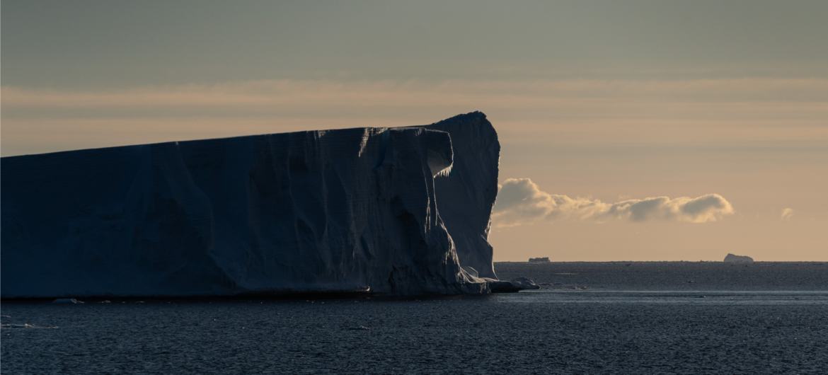 Um grande iceberg flutua na água durante a Expedição Internacional de Circunavegação Costeira da Antártida.