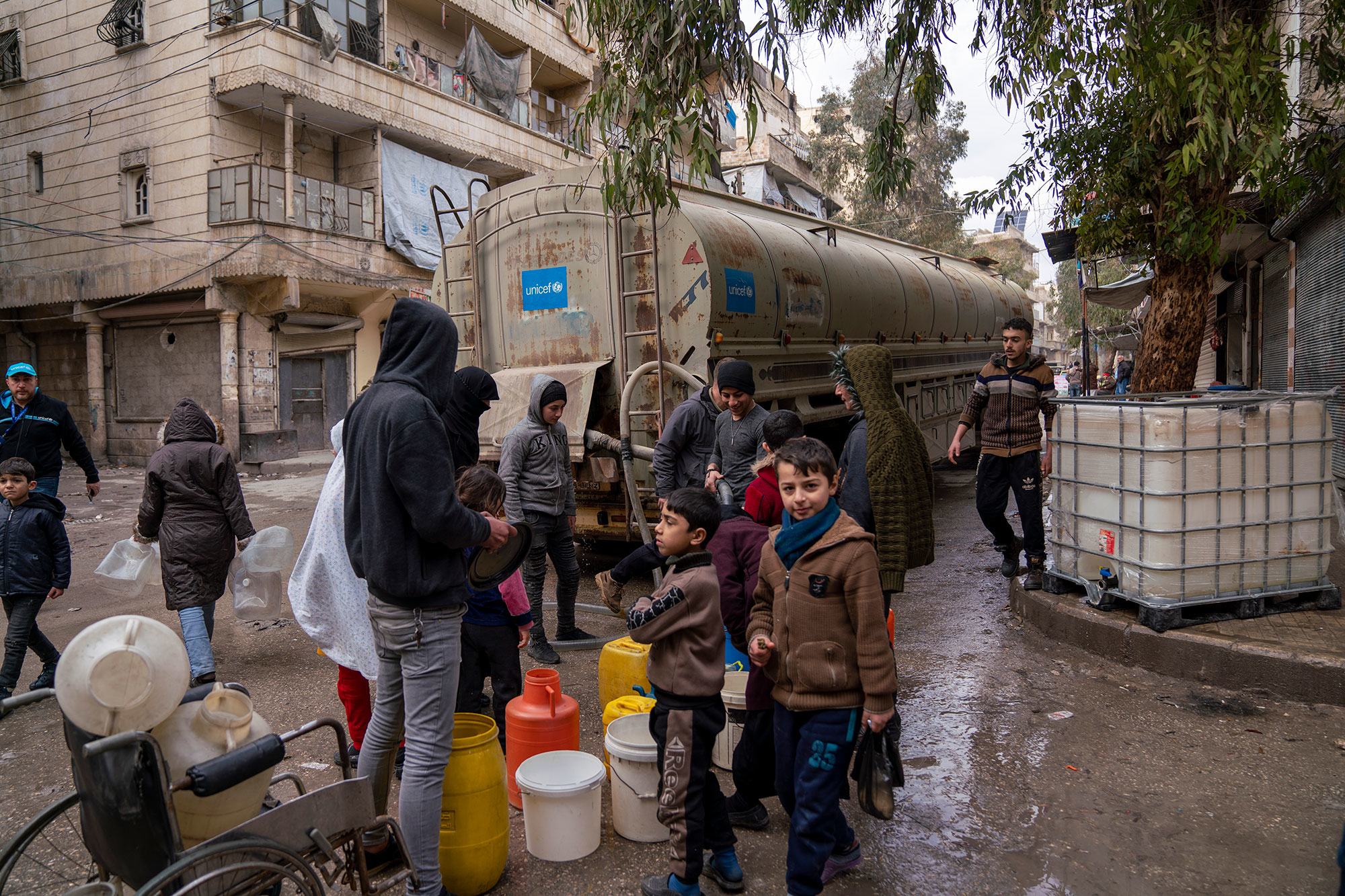 مواطنون يملأون العبوات بالمياه النظيفة في نقطة توزيع في حي الميسر في مدينة حلب شمال سوريا.