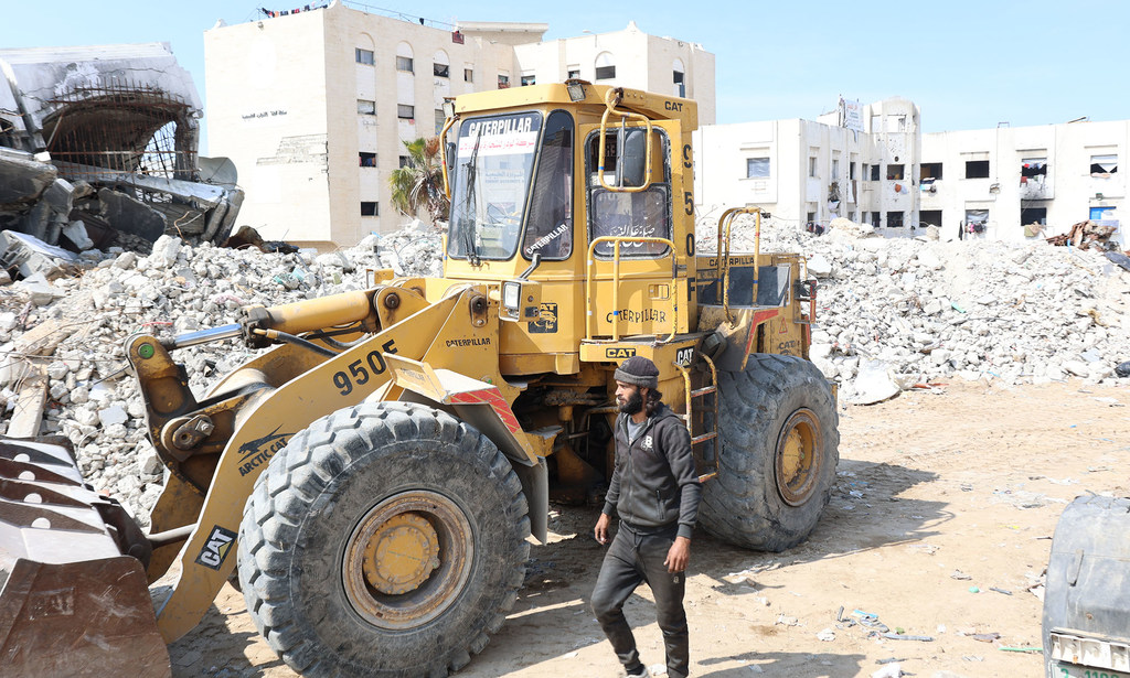 يعمل سائق جرافة على إزالة الأنقاض في غزة، بحثاً عن المفقودين تحتها.