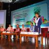20 जून, 2024 को नई दिल्ली में आयोजित UNOPS राष्ट्रीय सम्मेलन में एक छात्र मंच पर माइक्रोफोन में बोल रहा है। अन्य छात्र मंच पर मेजों पर बैठे हैं।