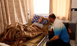 Ibrahim Al-Banna, sentado junto a su hijo Karim, herido de gravedad, lo consuela tras recibir el impacto de metralla cerca del riñón.