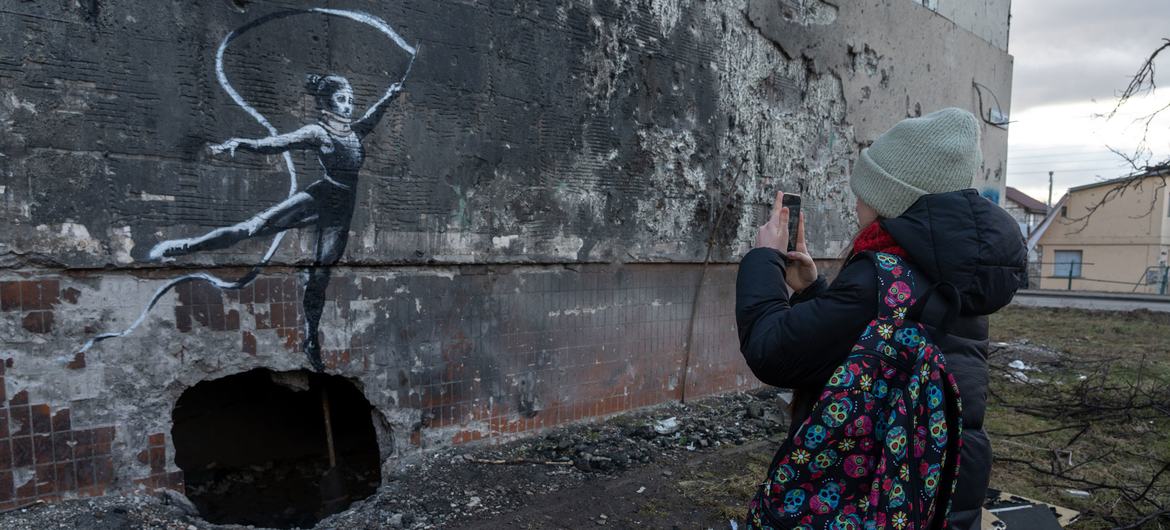 Un adolescent prend une photographie d’une œuvre de l’artiste britannique Banksy au printemps 2023 à Irpin. 