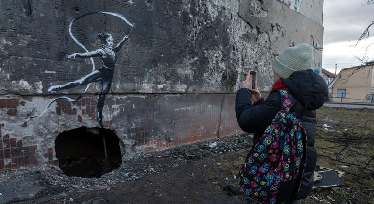 Un adolescent prend une photographie d’une œuvre de l’artiste britannique Banksy au printemps 2023 à Irpin. 