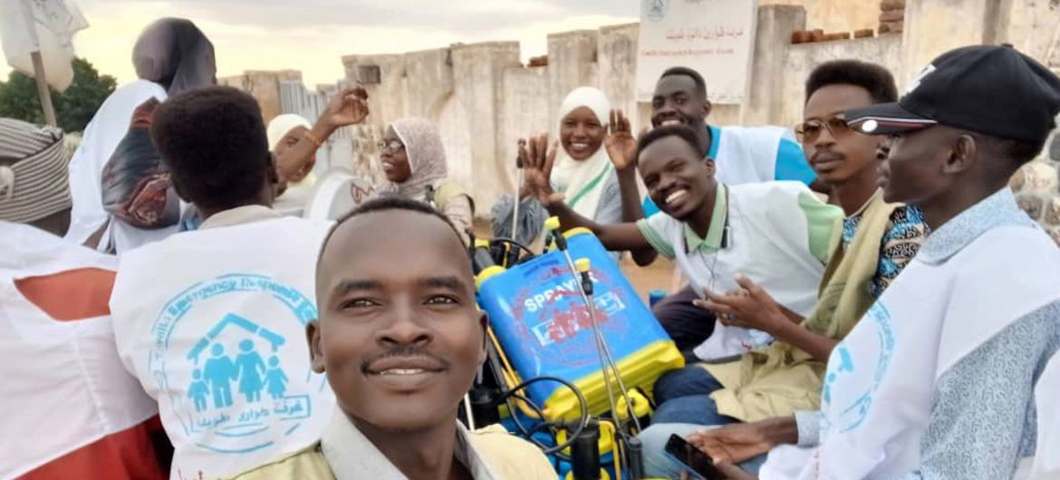 مجموعة من عمال الاستجابة للطوارئ يتخذون وضعية لالتقاط صورة في منطقة تويللا بشمال دارفور، مع وجود شخص واحد في المقدمة يلتقط صورة سيلفي.