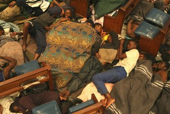 Des hommes dorment à même le sol de l'église méthodiste centrale de Johannesburg, utilisant les bancs comme appuie-tête. L'image montre une scène de foule de réfugiés cherchant un abri.