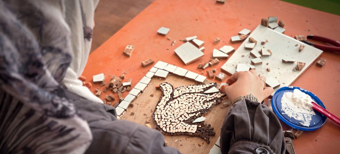 Une femme crée une mosaïque décrivant la colombe de la paix dans le camp de réfugiés de Za’atari, en Jordanie. 
