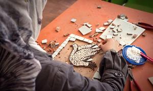 A woman crafts a mosaic depicting a peace dove in the Za’atari refugee camp in Jordan.