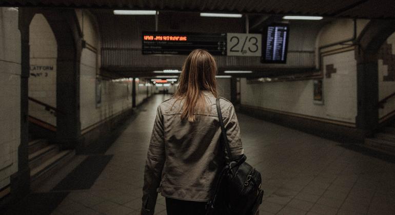 A woman walks through an underground tunnel.